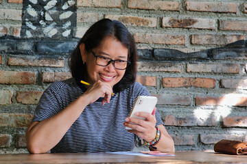 A middle-aged woman smiling cheerfully while looking at her smartphone