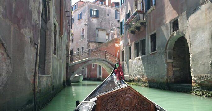 View from the front of the gondola of Venice canals, moored boats and architecture of the city during ride along one of the canals in Venice, Italy.