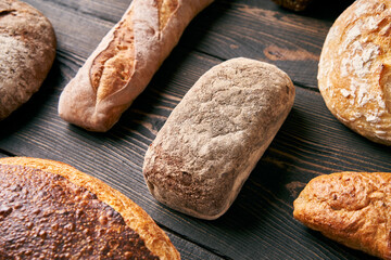 Various fresh loaves of bread on wooden background