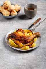 Grilled chicken leg with fried potatoes on gray background.