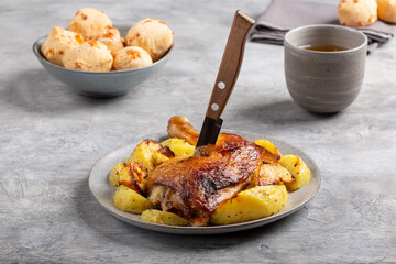 Grilled chicken leg with fried potatoes on gray background.