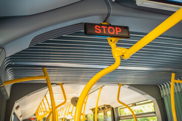 Stop sign in city bus. Empty bus interior. Bus with blue seats and yellow handrails