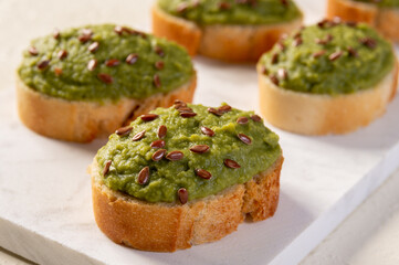 Mashed broccoli or green peas on slices of bread, sprinkled with flax seeds. Broccoli puree.