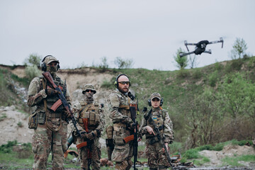 Four armed Ukrainian soldiers looking in the camera with a drone