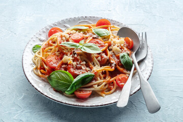 Spaghetti marinara, pasta with tomato sauce and basil, with a fork and a spoon, on a slate background. Italian dinner