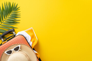 Dive into summer vacation vibes. Top view of a suitcase with beach gear, sunglasses, sunhat, towel, and palm leaves on a vibrant yellow backdrop, offering a blank area for text or advertising