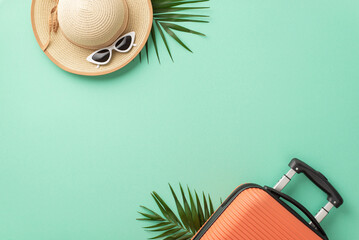An overhead shot of an orange suitcase, beach accessories, eyewear, sunhat, and natural palm leaves on a teal background, great for travel promotions