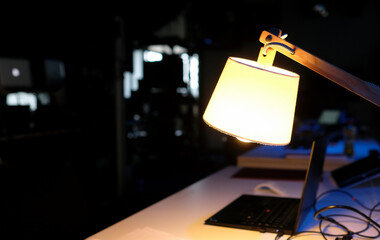 Working overtime - laptop in a dark room illuminated by a table lamp
