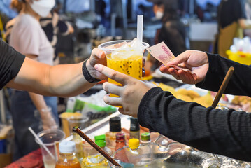 Vietnamese man sells passion fruit juice in plast cup in the night market in food festival