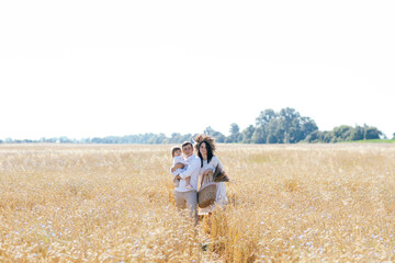 Happy childhood, family walking on the wheat field. Mother, father and little daughter leisures together outdoor. Parents and kid playing on summer meadow