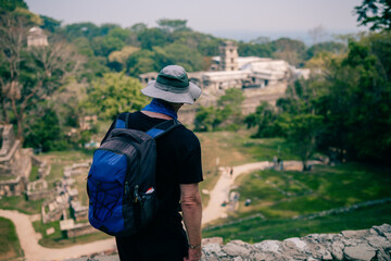Fototapeta na wymiar Hiker man with a hat looking at ancient Mayan ruins