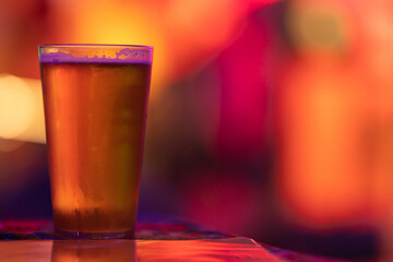 A glass of beer on the bar in a bright colorful setting