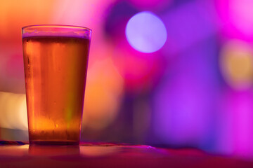 A glass of light beer on the bar in a bright colorful setting