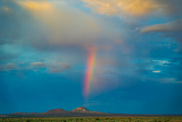 Rainbow peaking over a butte in the Mojave desert