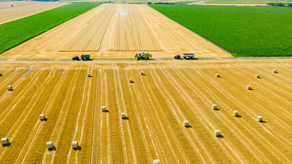 Aerial view over agricultural fields in harvest time, season, round bales of straw over harvested...