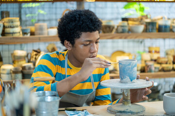 Fototapeta na wymiar Craftsmanship at its finest, African american boy shaping clay into unique and elegant vases.