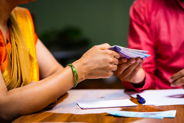 Close up shot of husband giving monthly expenses money to wife at home - concept of monthly budget,...