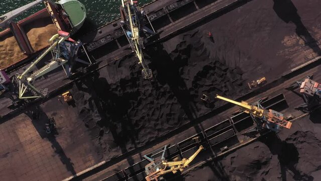 Sea port cranes uploading coal in train wagons. Aerial top view. Rapid speed motion.