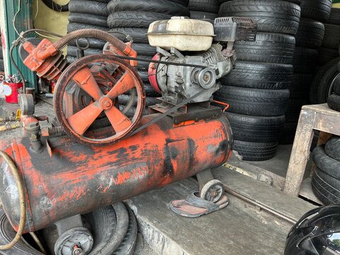 Old piston air compressor used in a auto shop for inflating car or motorcycle tire.