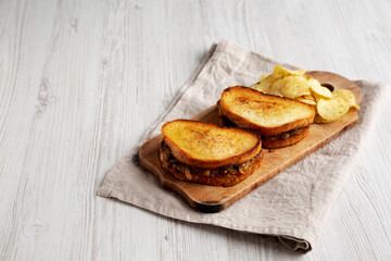 Homemade French Melt Sandwich with Caramelized Onion and Gruyure Cheese on a rustic wooden board, side view. Copy space.