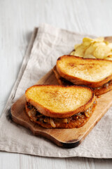 Homemade French Melt Sandwich with Caramelized Onion and Gruyure Cheese on a rustic wooden board, side view. Copy space.