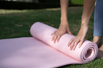 Close up of woman hand folding yoga mat on green glass, soft cute and thick mat.