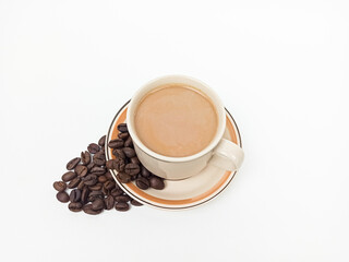 Cup of coffee with coffee beans isolated on white background. Milk coffee or caffe latte in a mug beside a pile of beans against a white background.