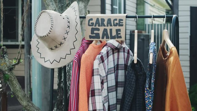 Garage sale, yard sale concept. Used clothes hang on floor hanger in front yard.