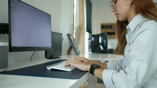 Young woman sitting and working in front of computer in her home, work from home concept, 4k video