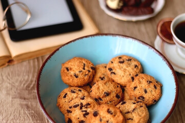 Plate of chocolate pralines, bowl of cookies, cups of tea, glasses of juice and lit candles on the table. Selective focus.
