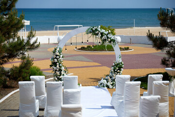 White wedding arch with white roses on the seashore