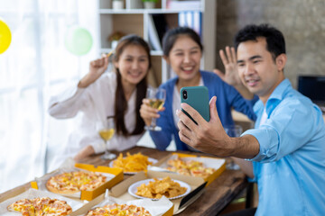 Let the party begin! Group of young people having fun together with champagne and pizza. Celebrating holiday in company office with friends. Young friends taking selfies together at home party.