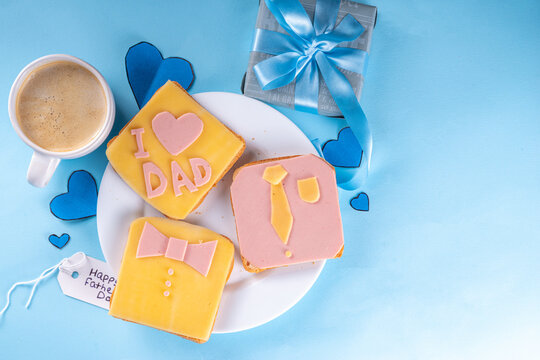 Father's day holiday idea, cute surprise gift. Child preparing breakfast for dad, creatively decorated toast sandwiches with tie, bow tie, inscription I love Dad. Top view copy space, blue background