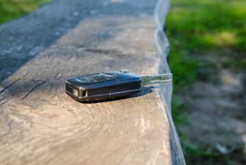 Abandoned,Forgotten car key on a wooden plank on a bench at summer park.Selective focus.