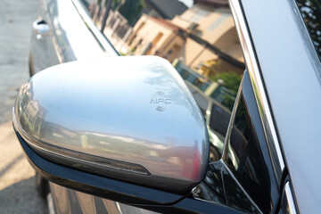 NFC sensor symbol on the car side mirror, this is position to using a NFC card to touch for unlocking the car door. Transporation technology symbol, close-up and selective focus.