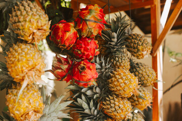 Pineapples and dragonfruits hang on the tent. Exotic fruits on the street