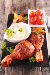 Roasted chicken drumsticks on plate with french fries and dipping sauce