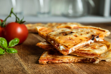 Slices of homemade pizza waffle with tomato sauce, pepperoni, olives and parmesan cheese on a cutting board