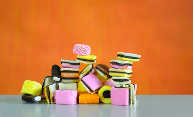 Tuinposter liquorice confectionery on orange background,multicolored and colorful sweet food,sweets or candy concept © Kirsten Hinte