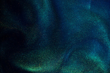 Gold Dust Particles Creating Shiny Waves in a Blue Liquid with a Green Tint. Glittering golden...