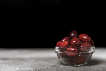 Red olives on a marble background. Various types of olives in bowls and olive oil with fresh olive leaves. Copy space. Place for text. Mediterranean food. Vegan.