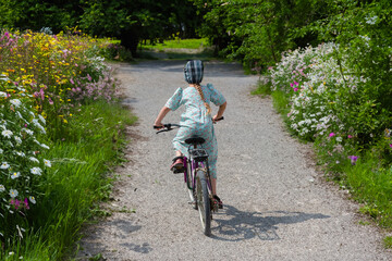 Young Mennonite girl on bicycle down the path