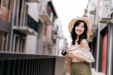 Fototapeta na wymiar Happy youth asian woman with camera travels street city trip on leisure weekend. Young hipster female tourist sightseeing summer urban Bangkok destination. Asia summer tourism concept.
