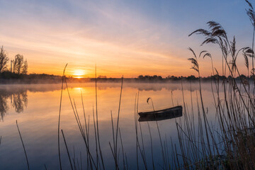 An old fishing boat on a lake during a beautiful sunrise