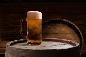 mug of beer, wheat ears, green hops and beer barrel on a wooden background. High quality photo