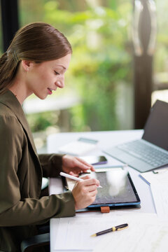 Concept of business office woman working,Businesswoman smile while working about her invesment plan with analyzing document and business investment graph data by using laptop on desk in workstation.