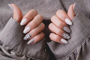 Woman's hand with a beautiful oval-shaped manicure. Autumn trend, beige color polishing with...