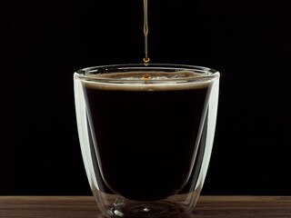 coffee translucid glass with droplet on wood surface and black background