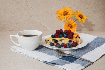 A piece of blueberry cheesecake on a white plate and a cup of coffee on a stone table. Front view
