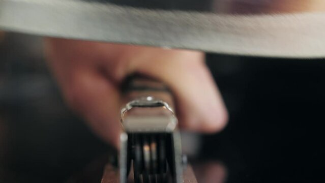 Man Sharpening the knife with a whetstone on a wooden background close up.